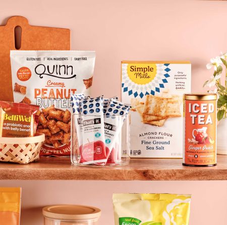 A shelf with a group of products, including a bag of peanut butter pretzels, fruit bars, and a box of crackers.
