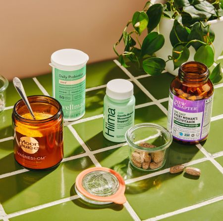 A countertop scene of supplements, including magnesium, probiotics, and a woman’s multivitamin.